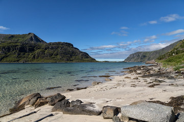A sandy beach with some fantastic clear water and mountains in the background