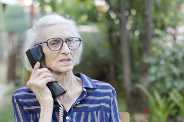 Old lady talking on the phone in the backyard