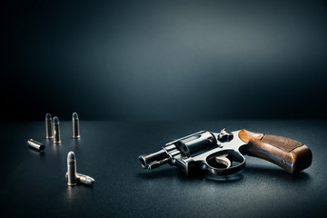 gun sitting on a table with bullet shells / dramatic lighting