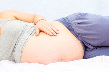 A pregnant woman is lying and stroking her belly