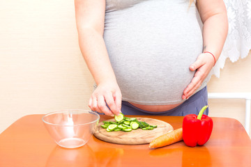 Obraz na płótnie Canvas Pregnant woman eating cut cucumber. Diet for pregnant women.