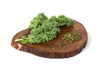 Kale leafs and pumpkin seeds on wooden cutting board