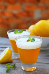 Tasty lemon jelly in glass on grey wooden background