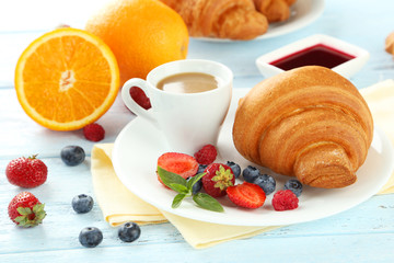 Fresh tasty croissants with berries on blue wooden background