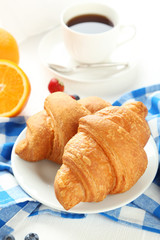 Fresh tasty croissants with strawberry and coffee on white woode