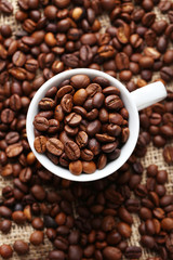 Coffee beans in cup on a sack, close up