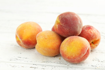 Ripe peaches fruit on a white wooden background