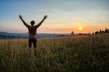 Fototapeta na wymiar traveller raising his arms in the sunset