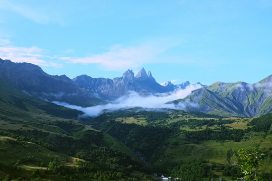 Overlooking floating clouds in the Arvan Valley with the Aiguilles d'Arves peak in the french Alps