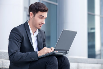 Cheerful young businessman is working with notebook 