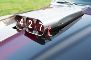 Muscle car hood close-up. Components of an automobile engine, throttle