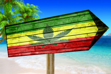Rasta Flag With Marijuana Leaf wooden sign on beach background