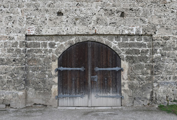 Fototapeta na wymiar Rustic cracked wall with old wooden door. Stone texture