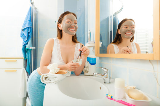 Woman applying mud facial mask