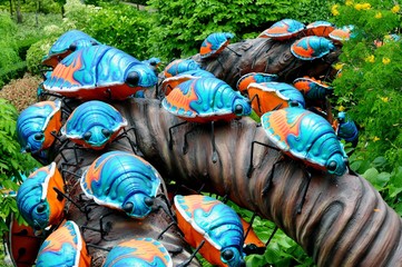 Cement bugs art climbing on the tree in a public park.