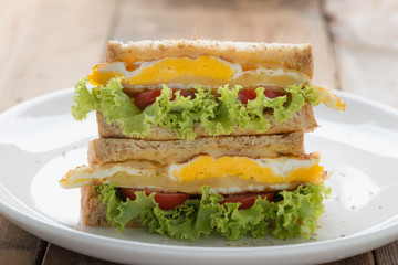 Sandwichs fried egg with cheese on white plate .