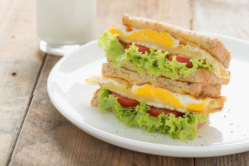 Sandwichs fried egg with cheese and milk on wood table.