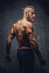 Shirtless muscular man with beard from his back.