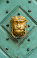 Golden lion knocker on the old green wooden door