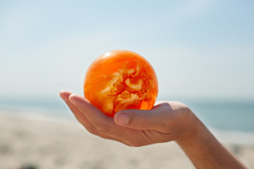 amber ball holding hand close up baltic sea background selective focus