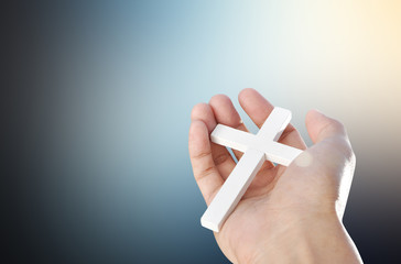 Hand and cross on dark light  background , concept design