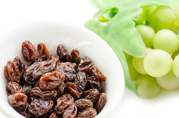 Obraz premium Dried raisins in white cup and fresh grapes