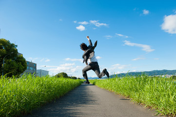 道路でジャンプをするスーツのビジネスマン