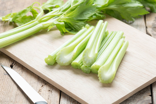 Fresh celery chopped on wooden cutting board.