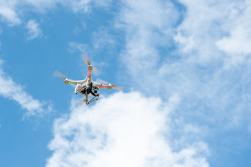 white drone hovering in a bright blue sky