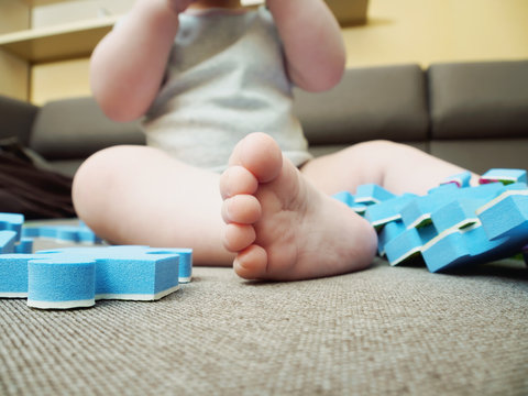 Foot of baby with puzzle pieces on sofa in the living room at home