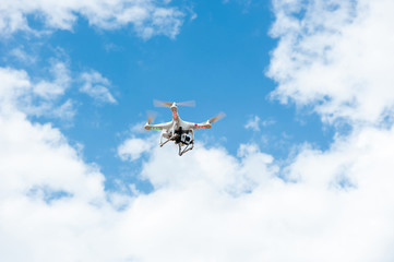 white drone hovering in a bright blue sky