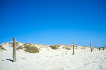 Backbeach view with cord fence and dunes under a clear blue sky