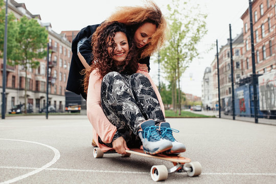 Young woman skating together on a longboard