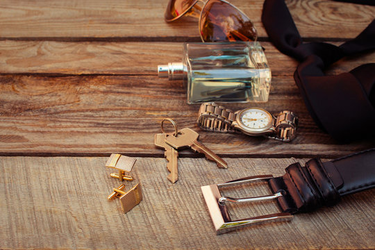 Men accessories: sunglasses, bag,  wrist watch, cufflinks, comb, strap, keys, tie, perfume on the old wood background. Toned image. 