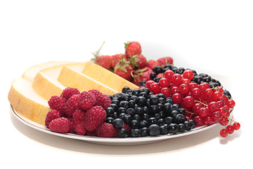 A plate of fruits: melon, strawberries, black currants, red currants, bilberries and raspberries.
