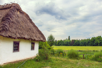 Fototapeta na wymiar Ukrainian hut thatched sloping field near