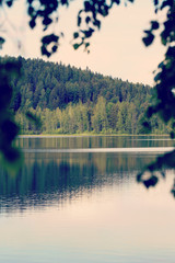 Amazing scenery from Finland. Water and forest with reflections. Image has a vintage effect applied.