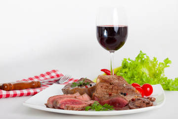 Beef steak on white plate with glass of red wine