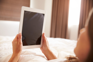 Woman Lying In Bed Whilst Using Digital Tablet