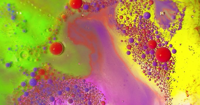 Color drops floating in oil and water over a colorful underground with oil painting effect. Shot on RED