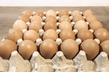 A lot of eggs in carton package on a wooden table ready for baki