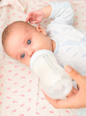 Mother feeding newborn baby from the bottle.