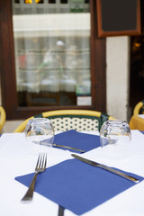 Table in outdoor restaurant with empty glasses and cultery.