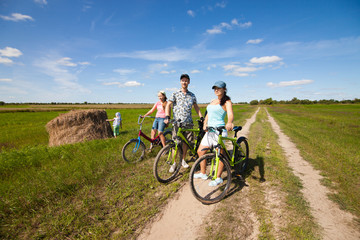 Fototapeta na wymiar Happy family on bikes standing in a field