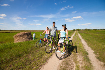 Fototapeta premium Happy family on bikes standing in a field