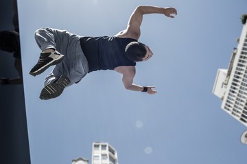 Athletic man doing back flip in the city