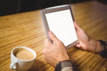Man drinking coffee and using tablet computer