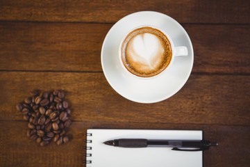 Cup of cappuccino and notepad with pen