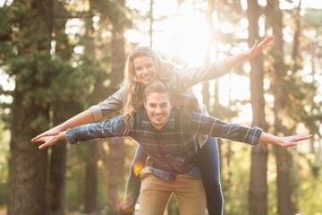 Smiling handsome man giving piggy back to his girlfriend