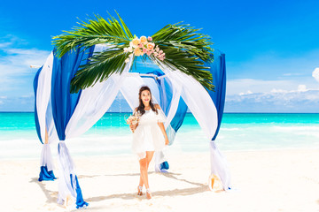 Wedding ceremony on a tropical beach in blue. Happy bride with a